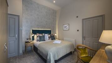 A hotel room with a large bed, bedside tables, a chair, and a desk.