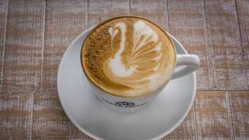 Une tasse de café surmontée d’un motif en latte, posée sur une soucoupe blanche.
