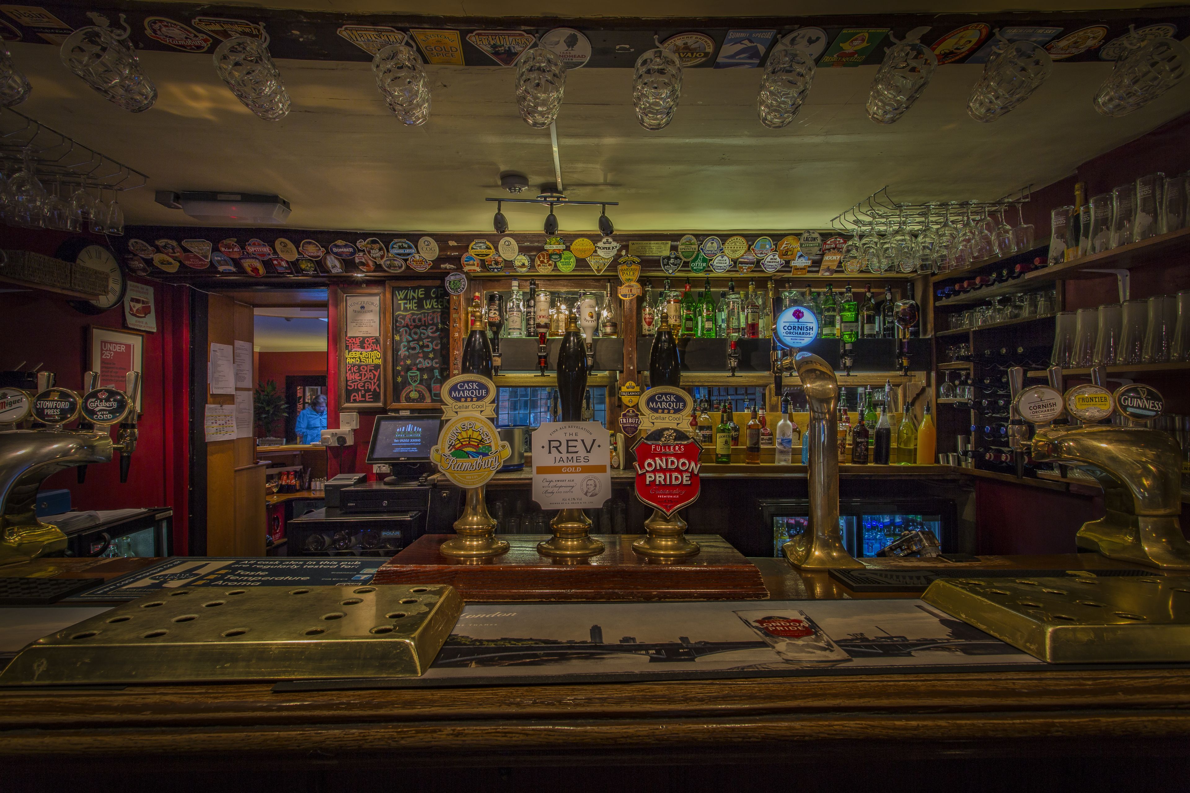 A bar with multiple beer taps, shelves with bottles, and a variety of glassware.