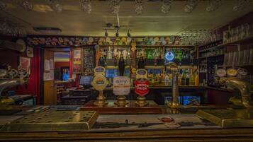 A bar with multiple beer taps, shelves with bottles, and a variety of glassware.