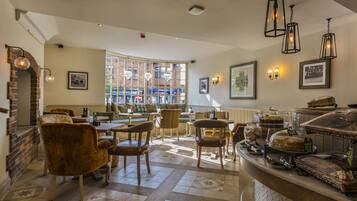 A cozy cafe with brick walls, wooden furniture, and a counter with baked goods.