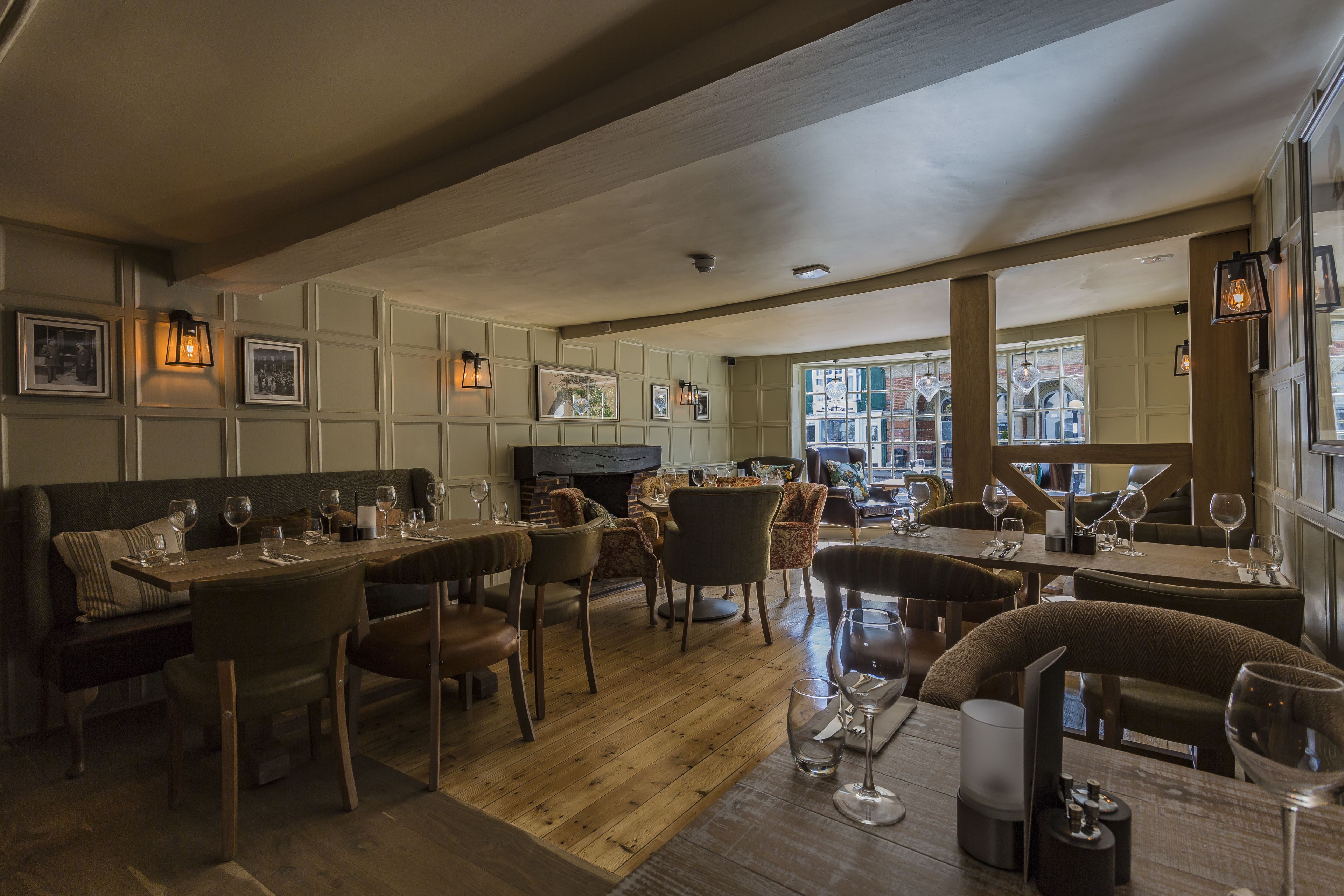 A restaurant with wooden flooring, cushioned seating, and framed pictures on the walls.