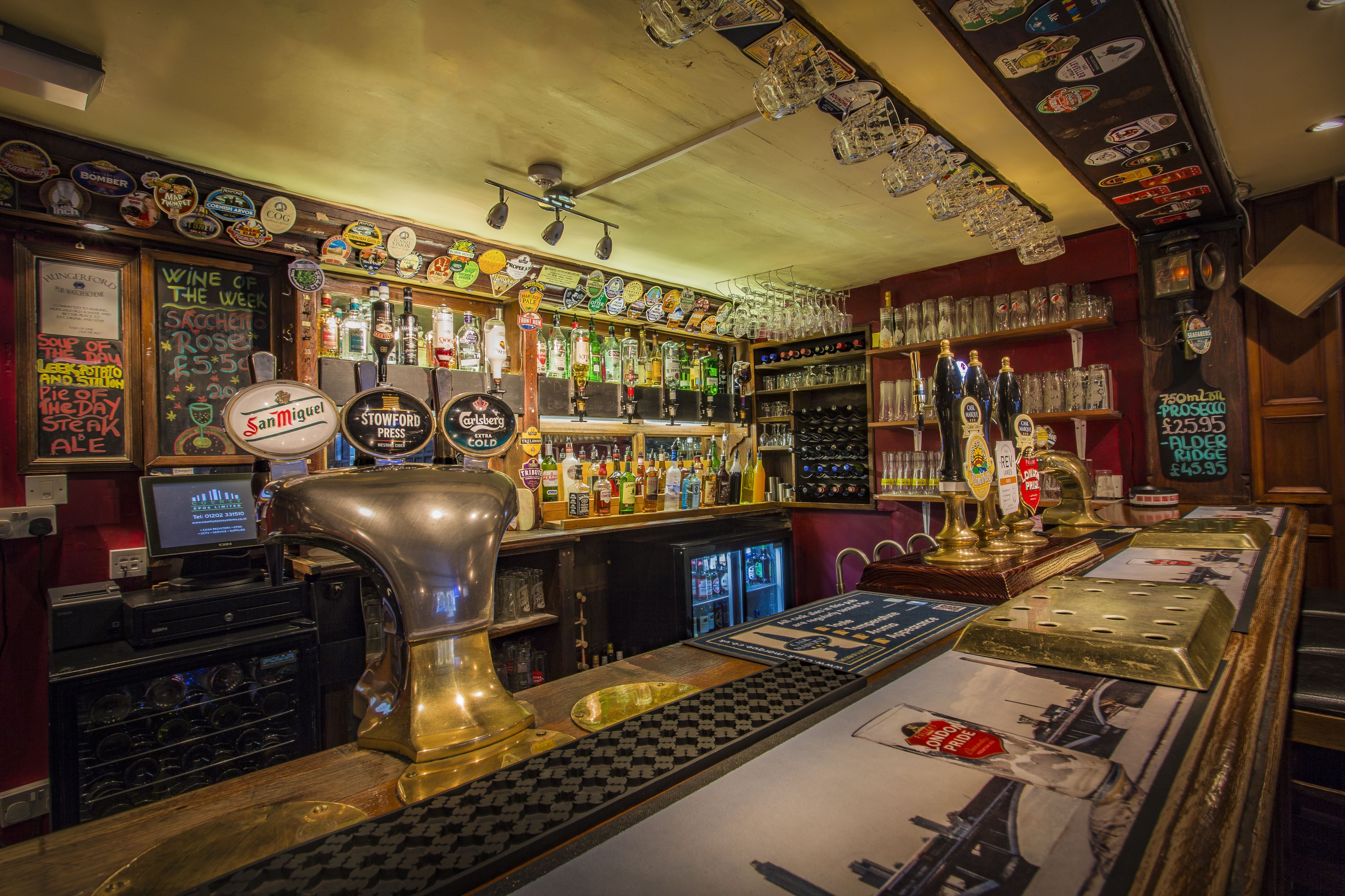 A bar with a variety of bottles and glasses, a jukebox, and a menu board.