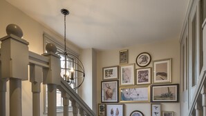 Eine Treppe mit Handlauf, Teppichstufen und einer Wand, die mit gerahmten Kunstwerken geschmückt ist.