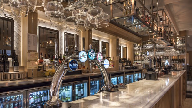 Eine Bar mit mehreren Zapfhähnen, darunter Guinness und San Miguel, sowie eine Auswahl an Flaschen und Gläsern.