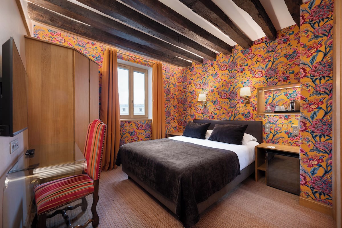 Ein Hotelzimmer mit Bett, Stuhl, Schreibtisch und Fenster.