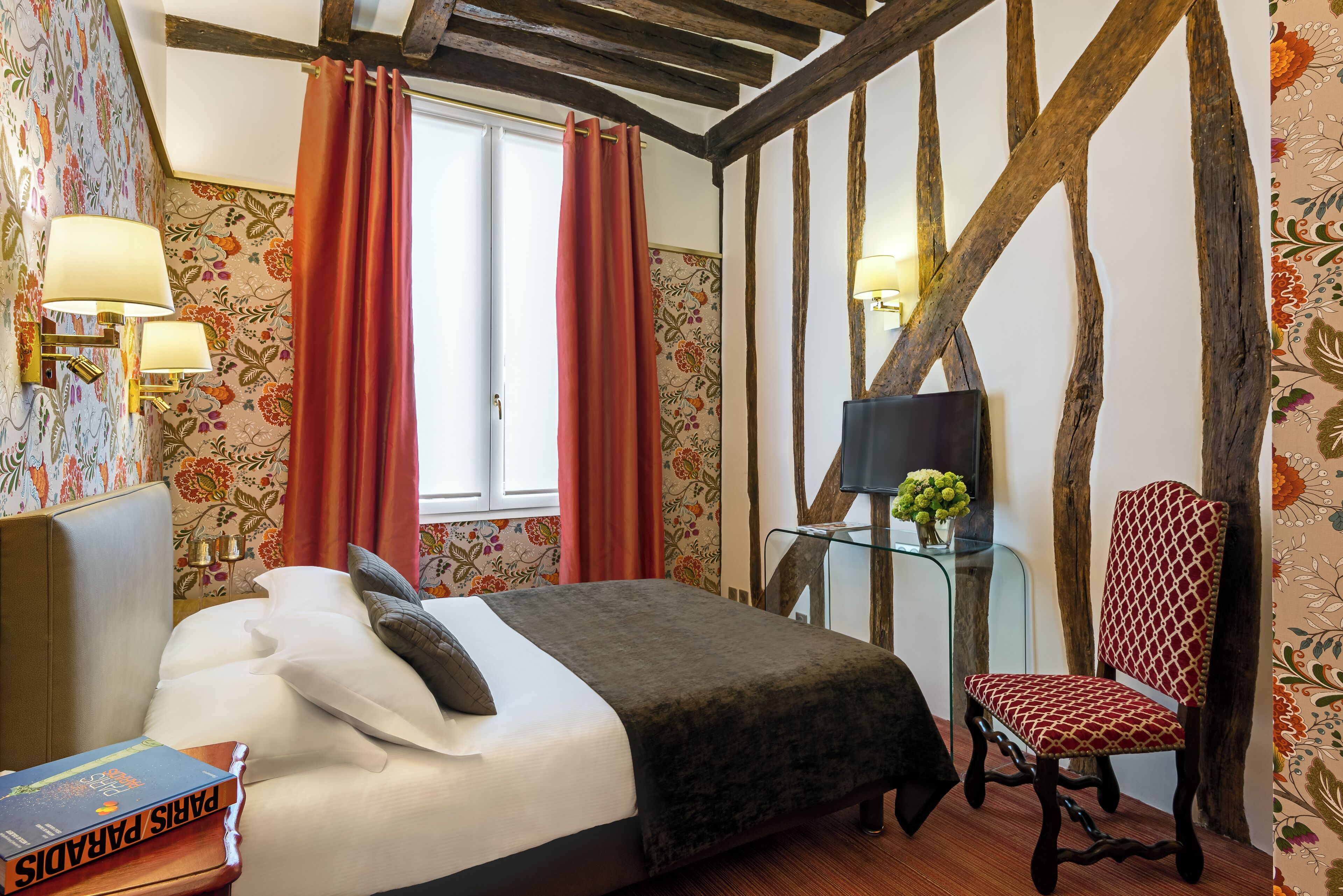 A bedroom with a bed, a chair, a nightstand, and a window with curtains.