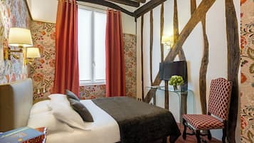 A bedroom with a bed, a chair, a nightstand, and a window with curtains.