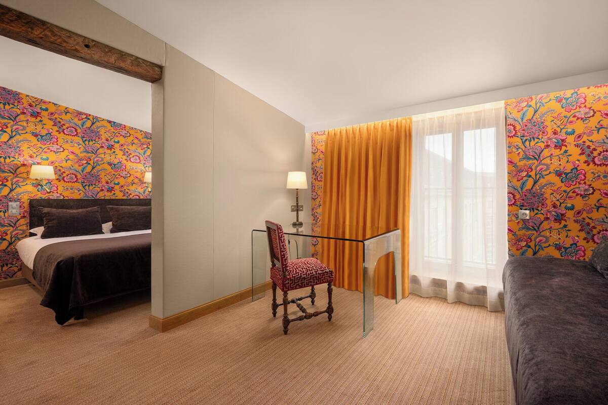 Ein Hotelzimmer mit Bett, Sessel, Schreibtisch und Sofa.