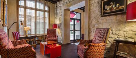 A room with stone walls, large windows, and zebra-patterned chairs.