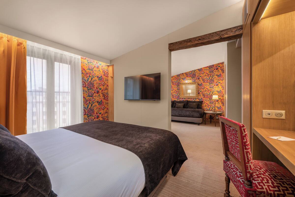 Ein Hotelzimmer mit Bett, Fernseher, Sofa und Schreibtisch.