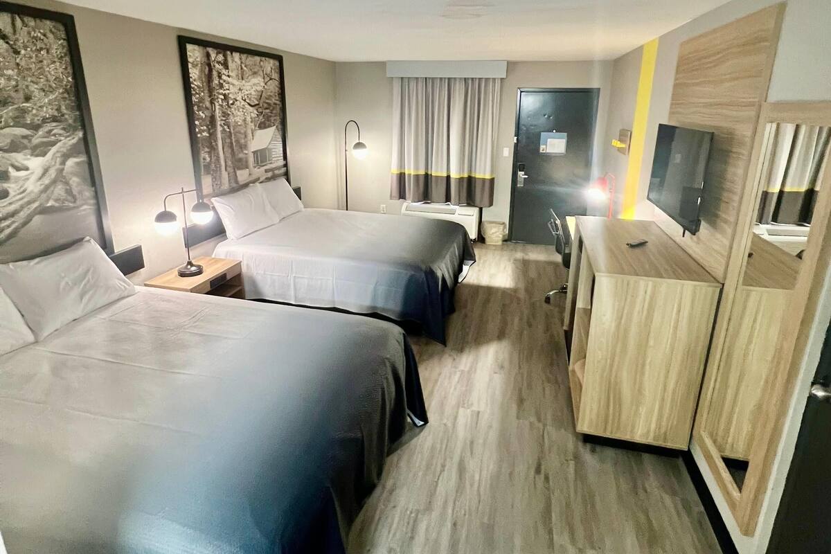 A hotel room with two beds, a desk, a TV, and a wardrobe.