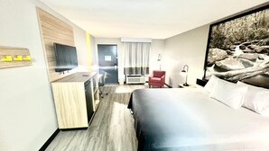 A hotel room with a bed, a desk, a chair, a TV, an air conditioner, and a painting on the wall. - Super 8 by Wyndham Manchester TN (Manchester)