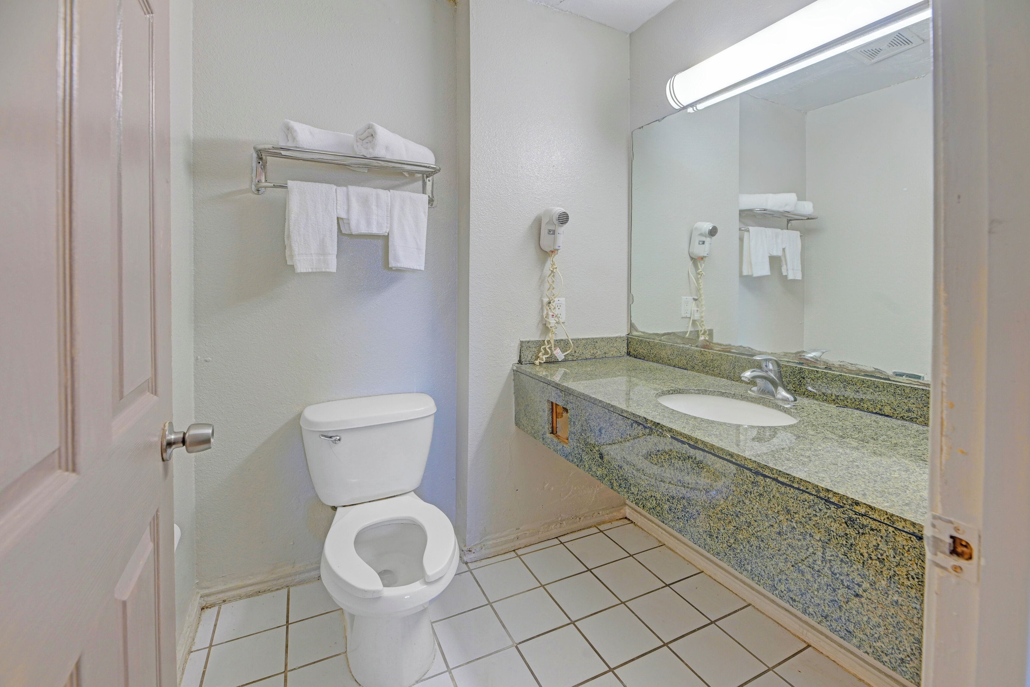 A bathroom with a toilet, sink, and a mirror.