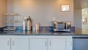 A kitchenette with a microwave, a coffee maker, and a small refrigerator. There are cabinets below the counter and a framed certificate on the wall. - Travelers inn by OYO Wichita Falls (Wichita Falls)