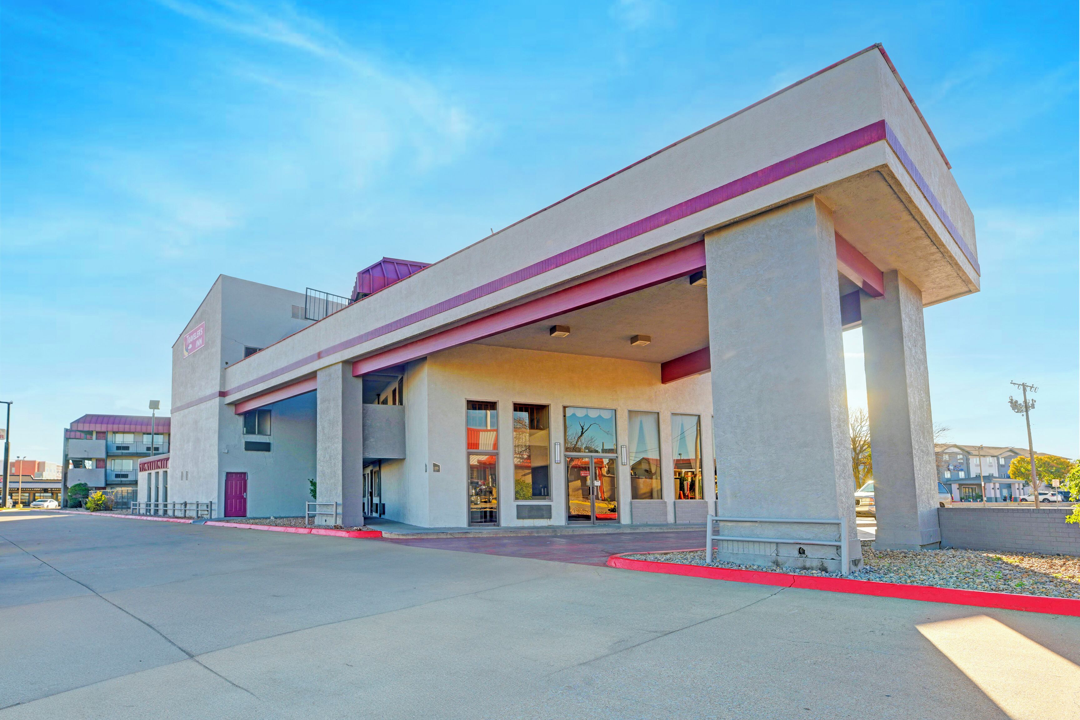A modern building with a flat roof, large windows, and a red curb.