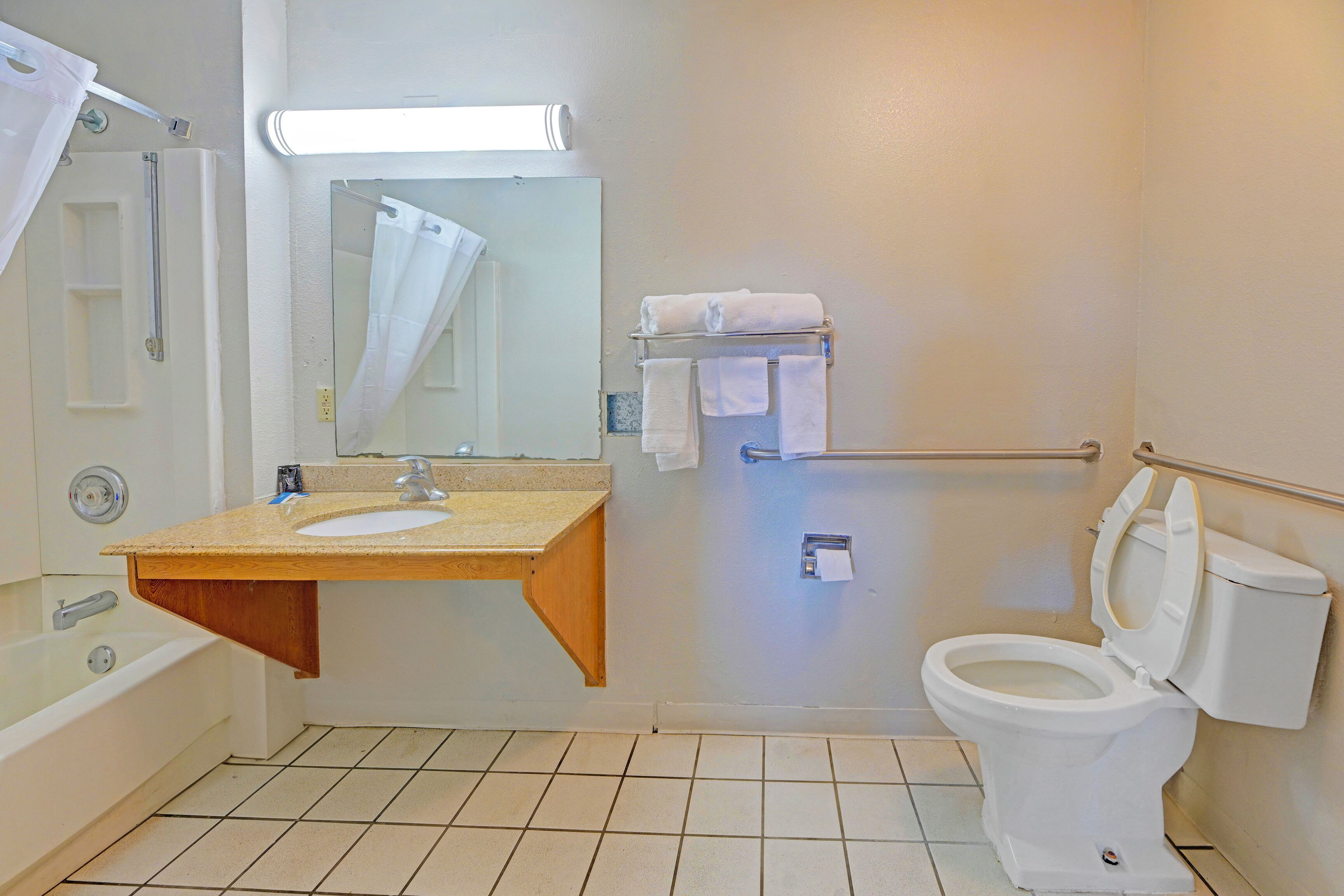 A bathroom with a bathtub, sink, mirror, toilet, and towel rack.