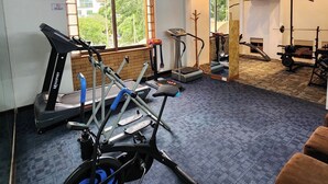 Une salle de sport équipée de matériel d’exercice, d’un tapis de course, d’un vélo d’appartement et d’un banc de musculation.