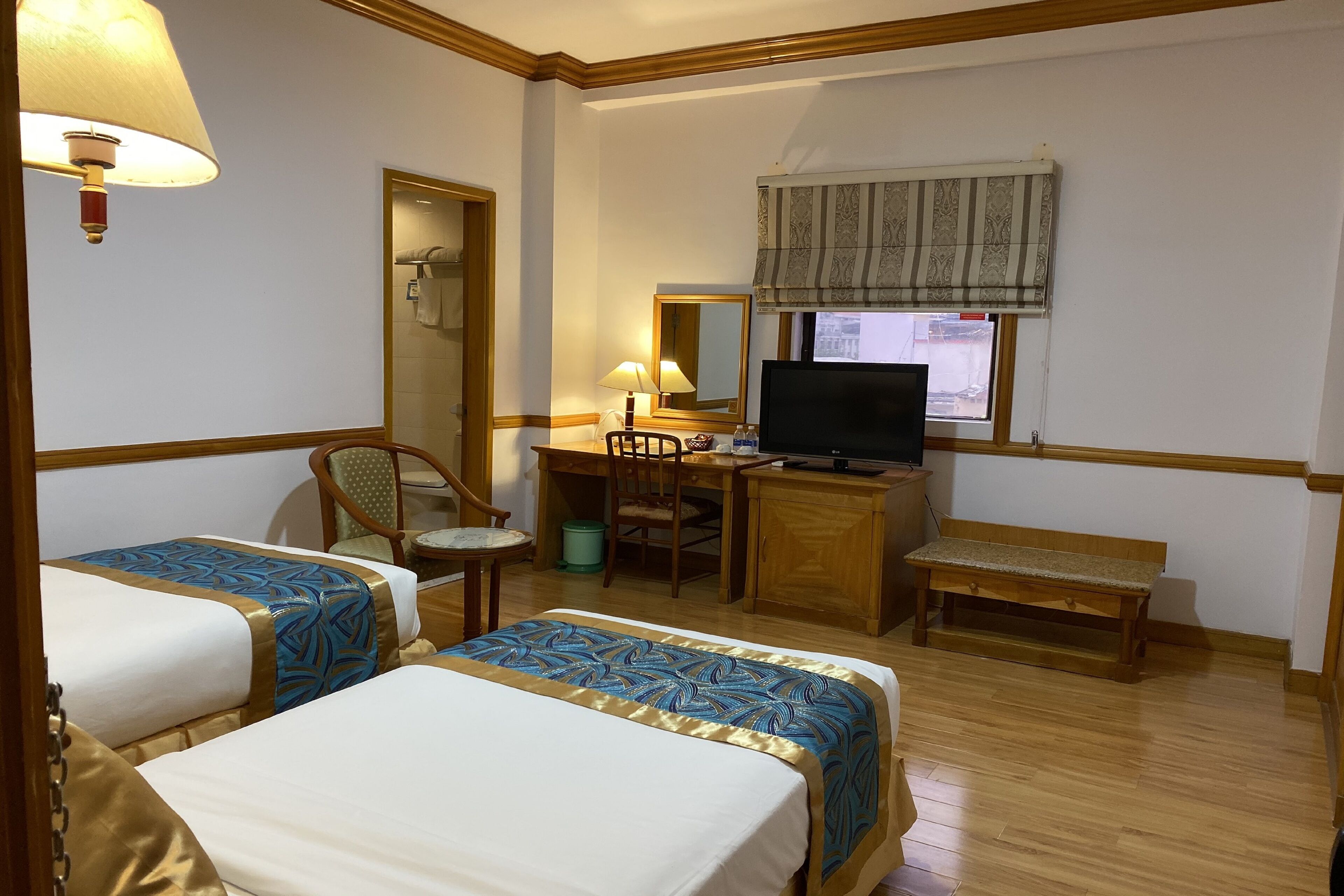 Une chambre d’hôtel avec deux lits, un bureau avec un ordinateur, une chaise, une télévision et une fenêtre donnant sur un paysage agréable.