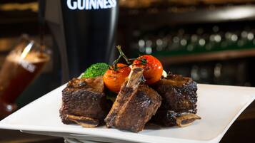 A plate of food with a Guinness beer mug in the background.