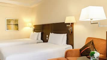A hotel room with two beds, a sofa, a small table, and a lamp.