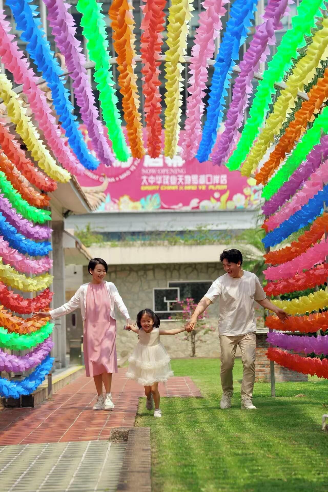 A family walking through a colorful paper archway.