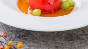 A white plate with a red spherical food item, green garnish, and a mushroom on top.