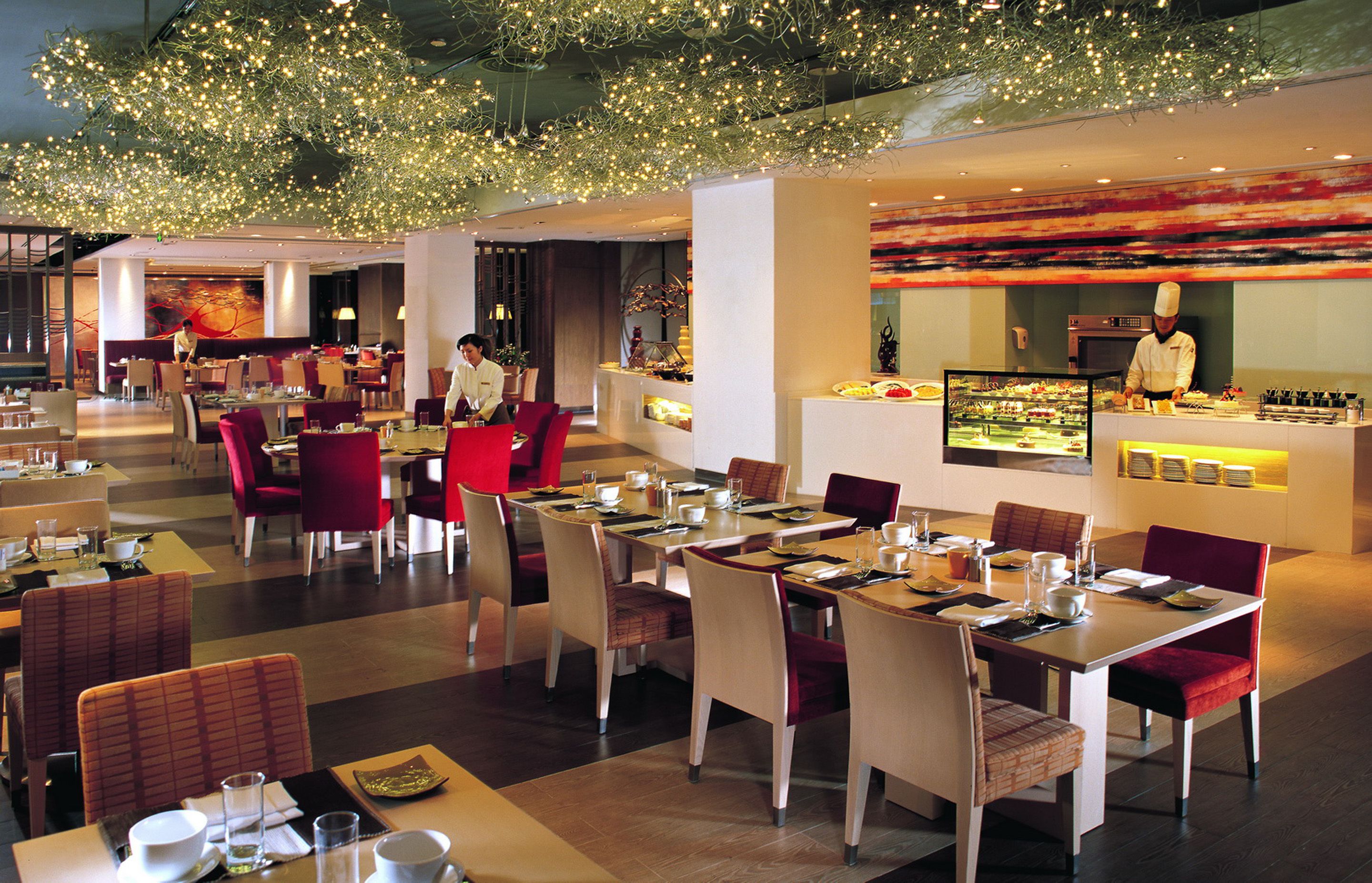 A modern restaurant with multiple dining areas, including a bar and a chef's station.
