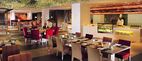 A modern restaurant with multiple dining areas, including a bar and a chef's station.