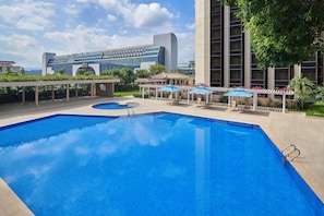 Una piscina al aire libre, sombrillas, sillones reclinables de piscina