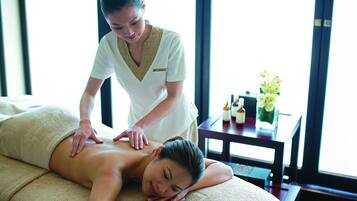 Experience a serene massage therapy session in a peaceful room with a large window and comfortable amenities.