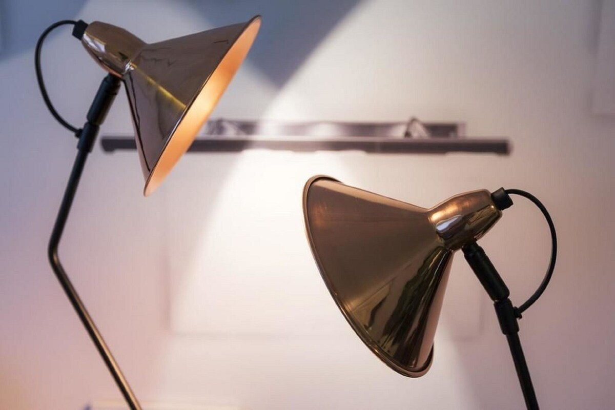 Two floor lamps with a metallic finish, positioned on a white surface against a plain wall.