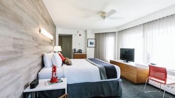 A hotel room with a bed, bedside table, lamp, red lantern, TV, and a window with curtains.
