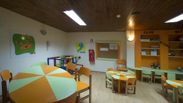 A classroom with wooden furniture, colorful tables, and educational posters on the walls.