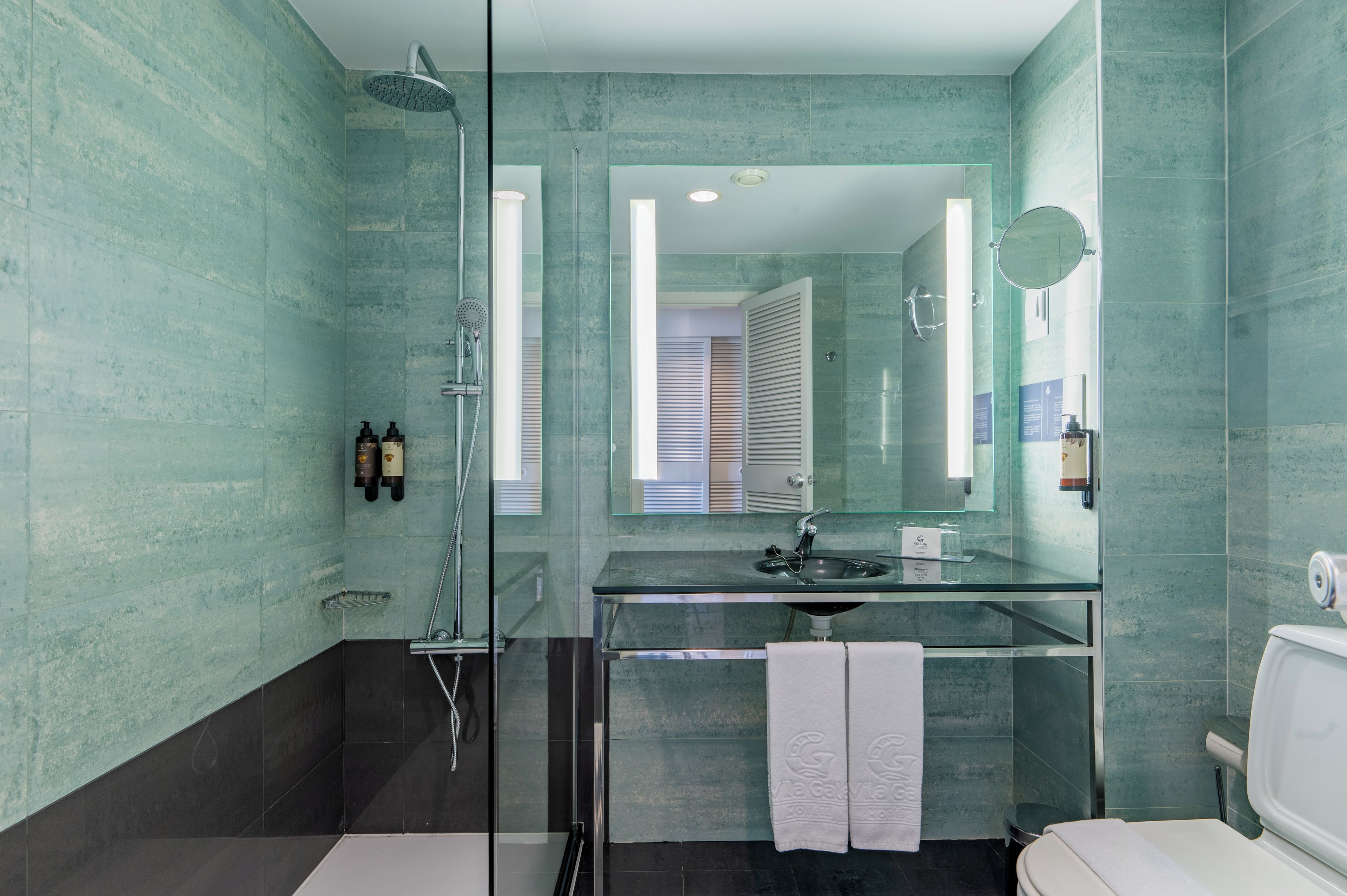 A modern bathroom with a glass shower enclosure, a sink with a mirror above it, and a toilet.