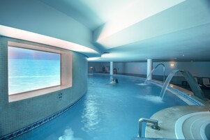 Una piscina techada, una piscina al aire libre, sombrillas