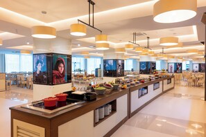 A modern hotel lobby with a long reception desk, multiple seating areas, and a large digital display. - Vila Gale Ampalius Resort Hotel (Loulé)