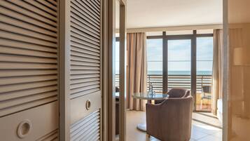 A hotel room with a balcony, a round glass table, and a chair.