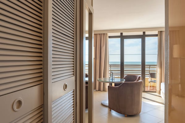 Una habitación de hotel con balcón, una mesa redonda de vidrio y una silla.
