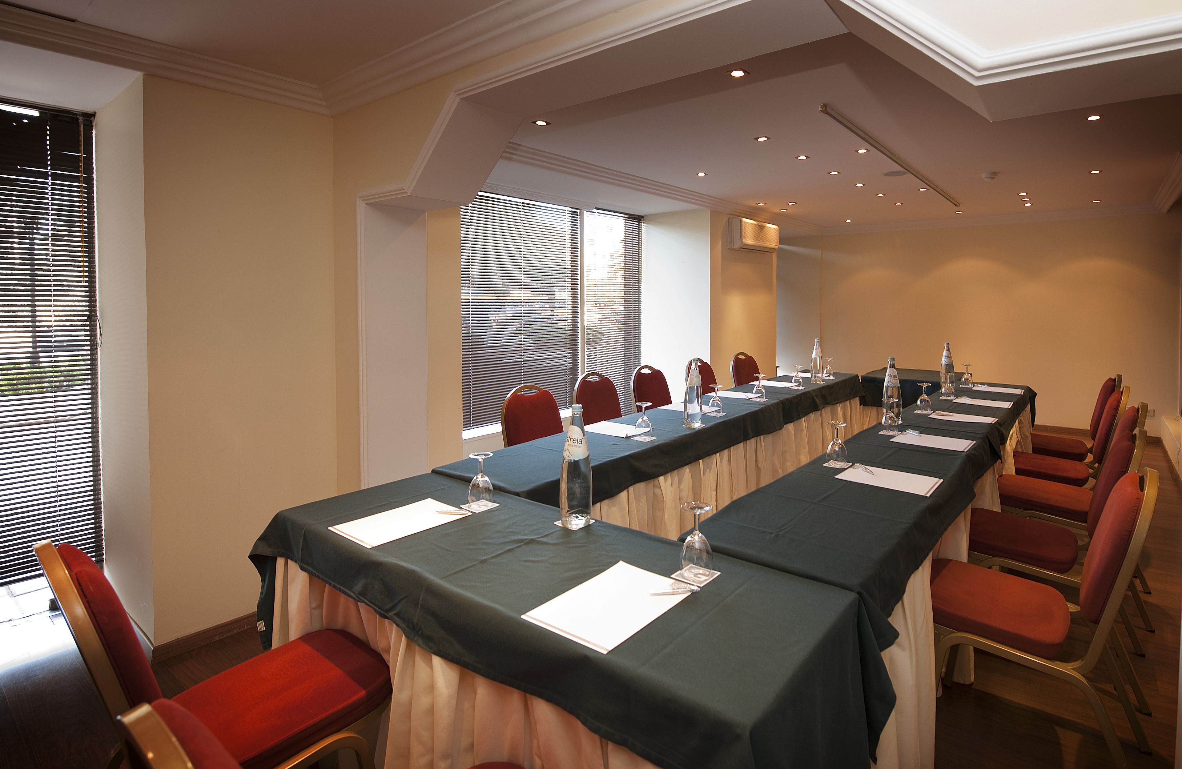 A conference room with a long table, red chairs, and a black tablecloth.