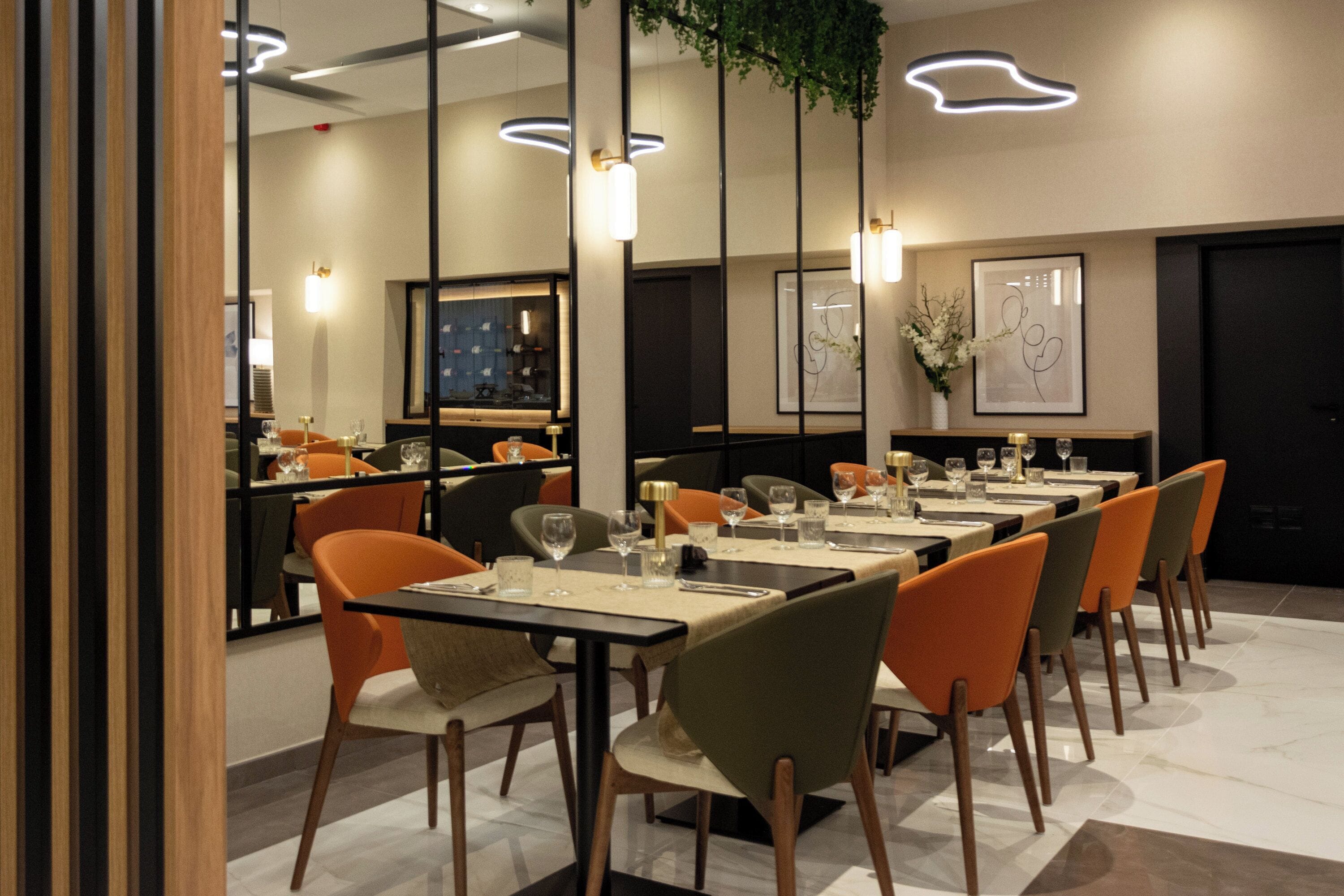 A modern dining area with multiple tables and chairs, a bar area, and framed artwork on the walls.