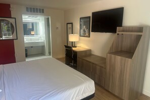 Een hotelkamer met een bed, bureau, stoel, televisie en raam.