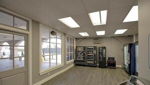 A spacious room with large windows, a vending machine, and a control panel.