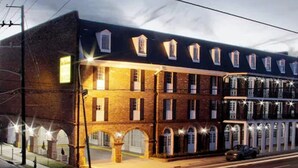 A multi-story building with a brick facade, multiple windows, and a well-lit entrance.