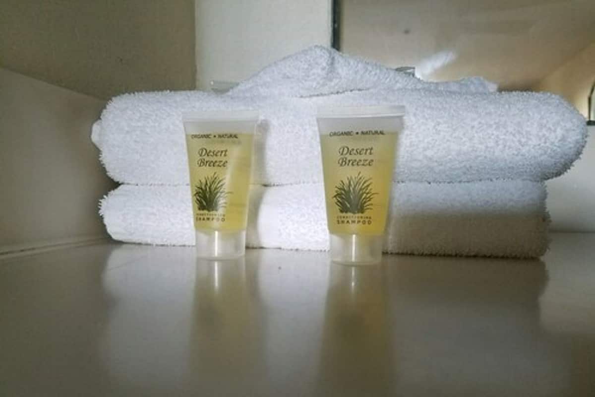 Two tubes of Desert Breeze shampoo and a stack of white towels on a reflective surface.