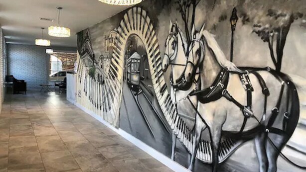 A hallway with a mural of a horse and carriage, tiled flooring, and hanging lights.