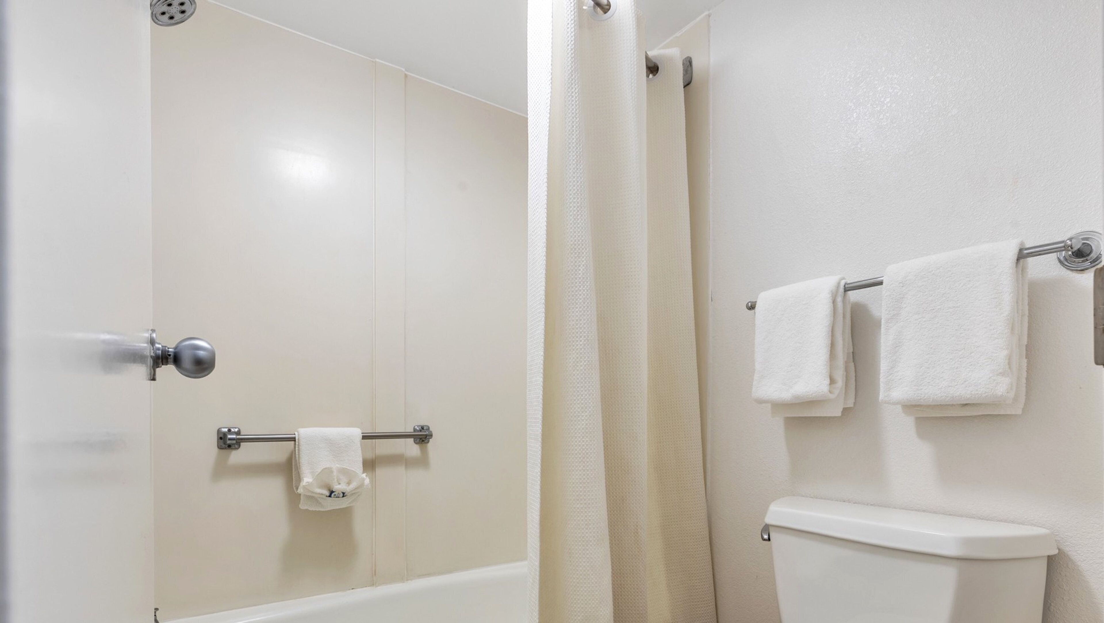 Un baño con ducha, inodoro y barra para toallas.