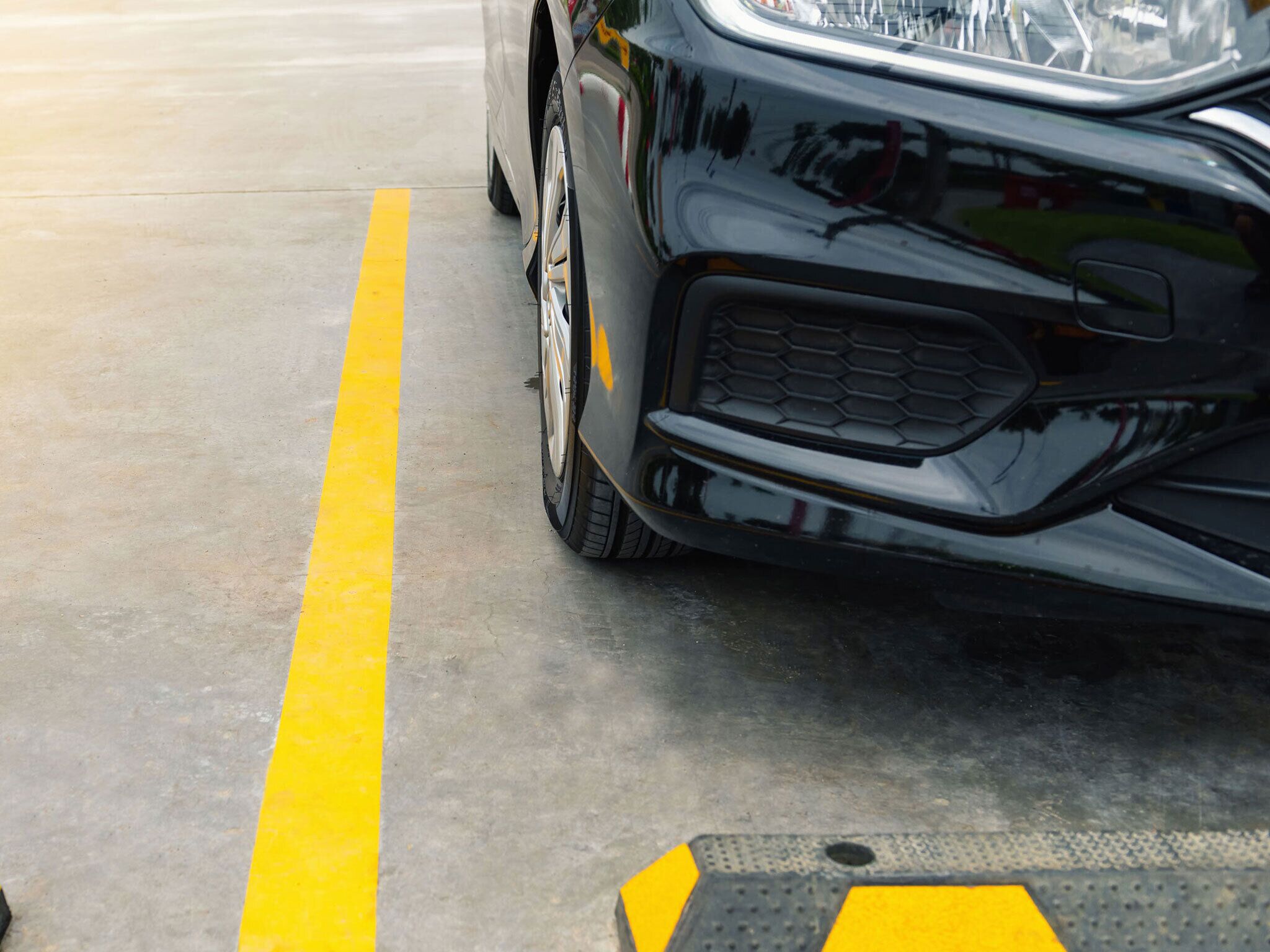 A car parked in a parking space with a yellow line on the ground.