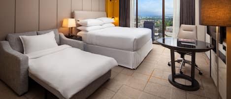 Habitación de hotel con una cama grande, una cama más pequeña, un sofá, un escritorio y vistas a la ciudad.
