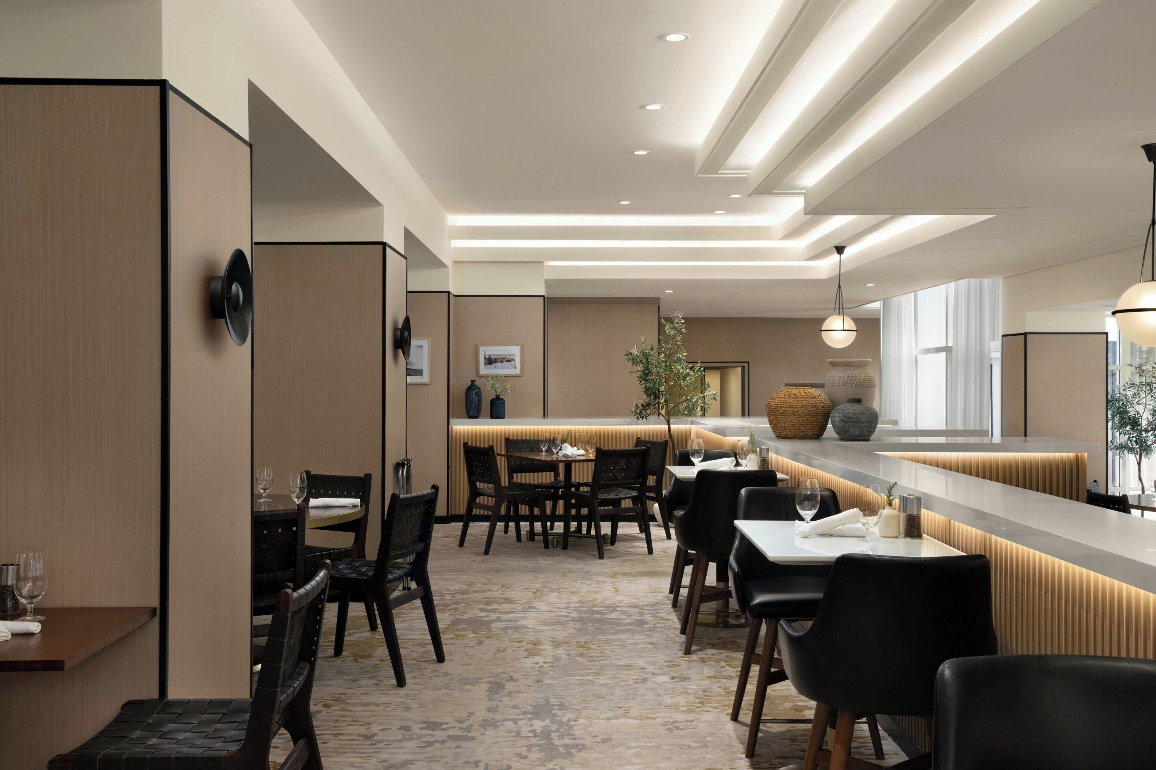 A modern hotel lobby with a central bar area, seating arrangements, and a decorative plant.